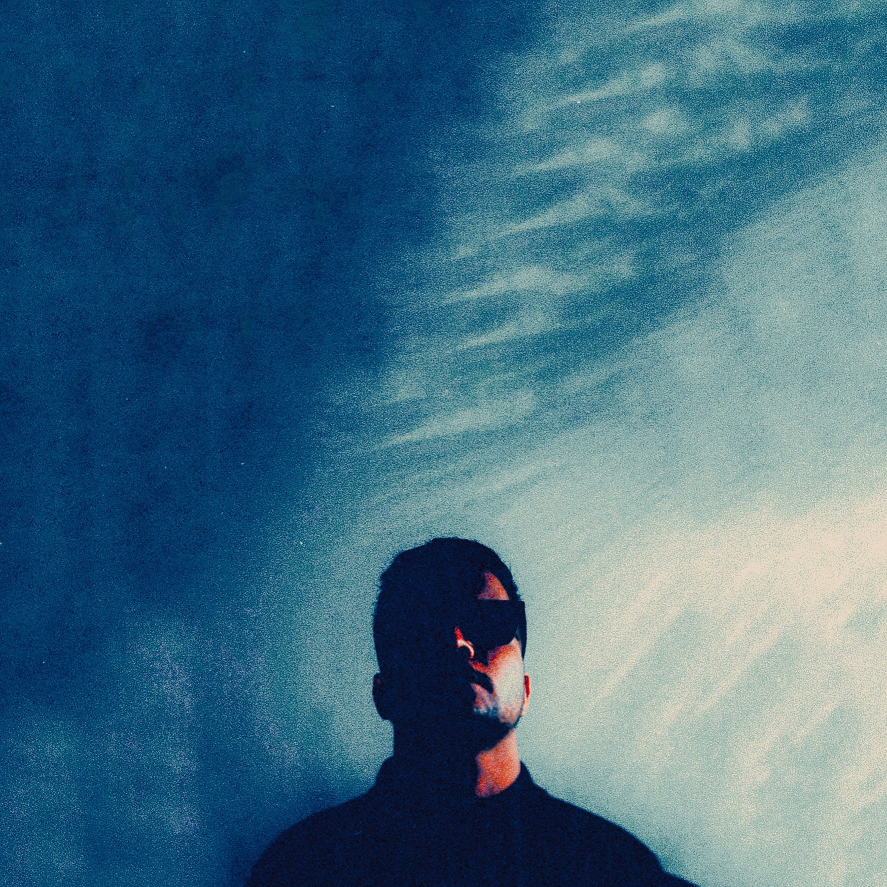 Blue-toned cinematic portrait of AYSH beneath an expansive sky