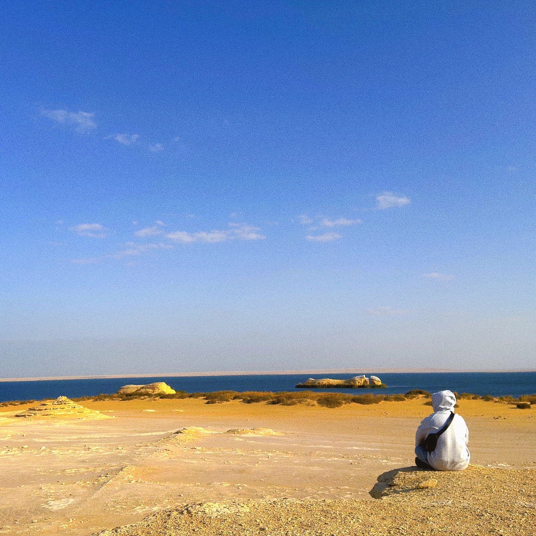 AYSH looking across a desert coastline beneath a wide blue sky
